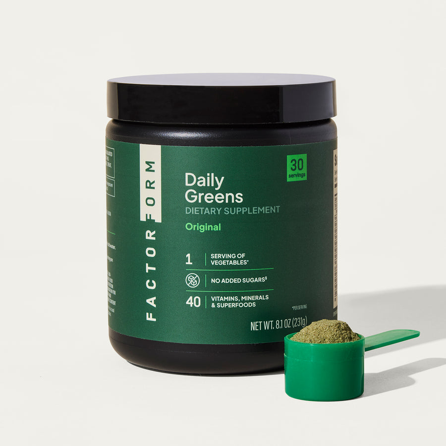 Green supplement container labeled 'Daily Greens' with a scoop of powder on a white background